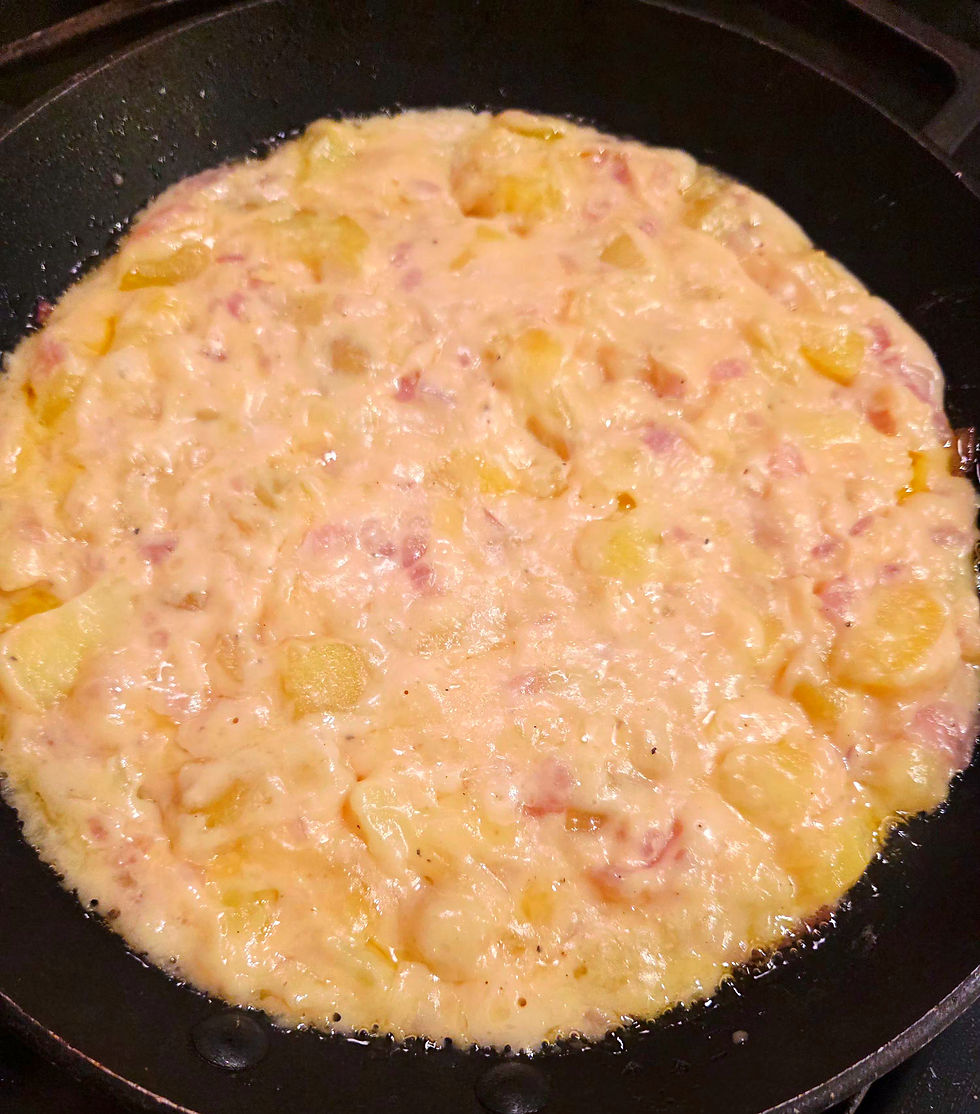 A skillet of potatoes, red onions, and montasio cheese cooking to make frico.