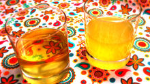 Two glasses of limoncello: the left one is made with vodka and is clear and the on the right is made with grain alcohol and is cloudy.