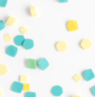teal and yellow confetti on a white background, very few pieces of confetti on the backgro
