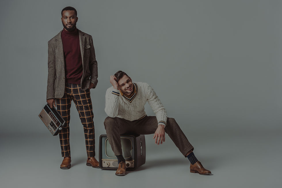 Two stylish men pose with vintage TV and radio