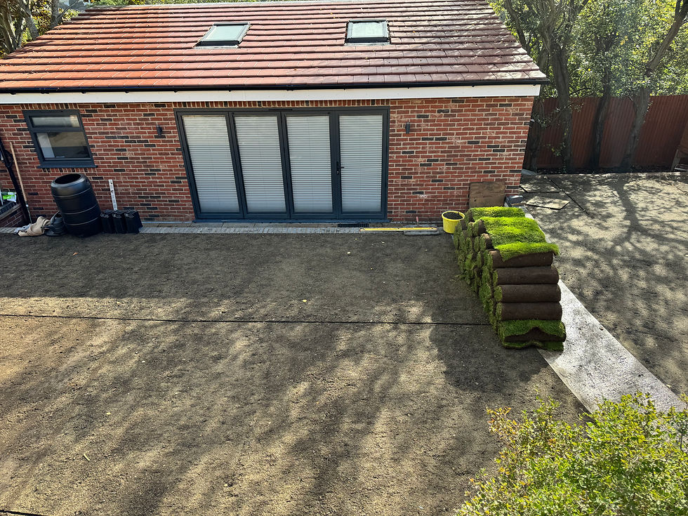 A view of an outbuilding showcasing its neatly crafted brickwork, set against a clear sky. The structure features a modern design with skylights and large windows. Stacks of rolled turf in the foreground hint at ongoing landscaping work.