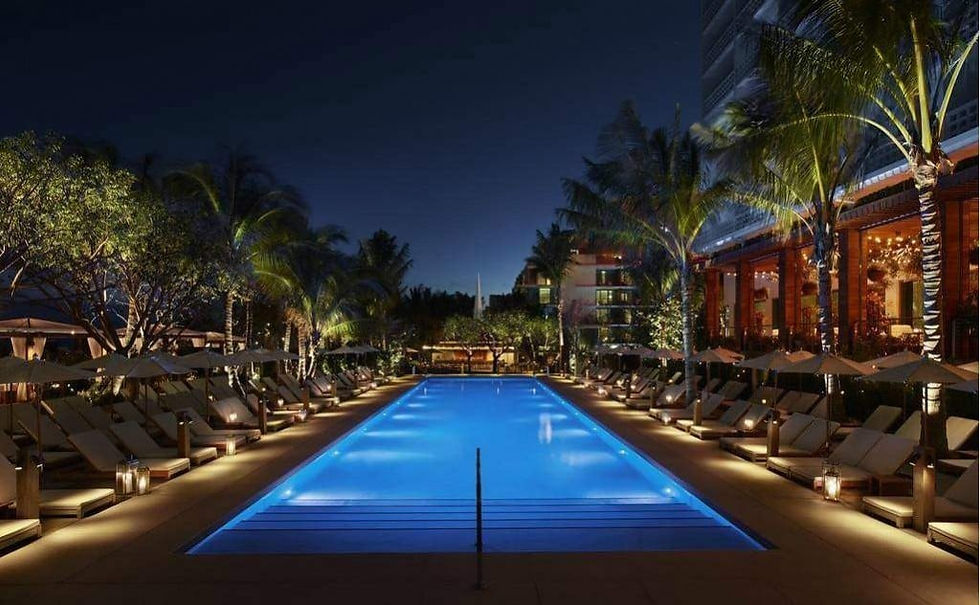 Luxurious pool area lit at night, surrounded by palm trees and lounge chairs. Soft lighting creates a tranquil, inviting atmosphere.