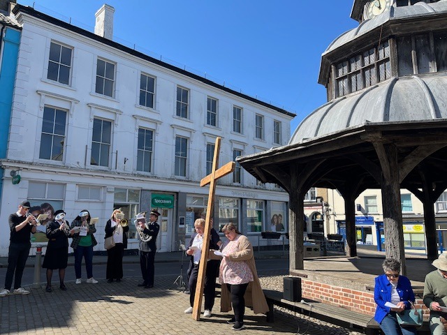 a group of people standing in North Walsham with a large cross