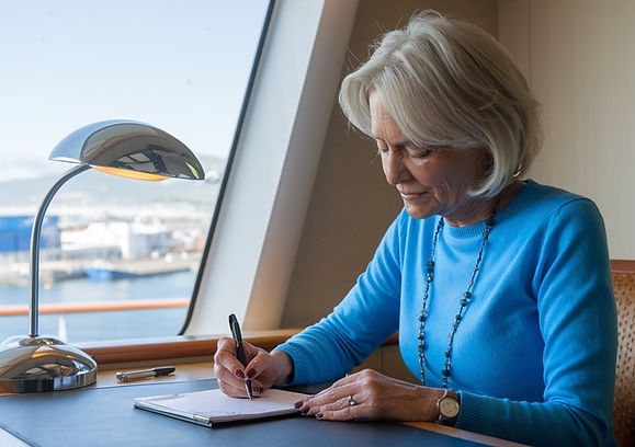 Older-lady-casually-dressed-writing-at-a-desk-on-a-cruise-ship-at-Port-of-Gibraltar.jpeg