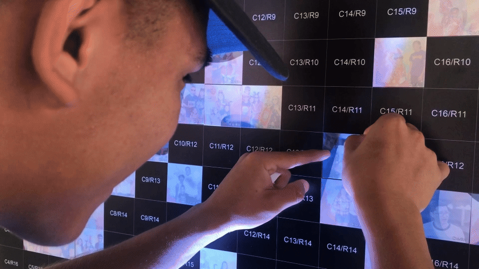 Young man excitedly placing his photo onto the mosaic wall at Pop Goes The Fort 2019—by Funboxx Photo Booths.