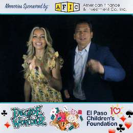 Two guests using the photo booth at The El Paso Children's Foundation event. The woman writes 'Viva El Paso Child. Foundation!' while the man writes 'Viva El Amor'—by Funboxx Photo Booths.