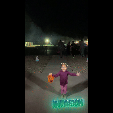 Adorable little girl playfully 'abducted' by candy-snatching aliens at a Halloween event—by Funboxx Photo Booths.