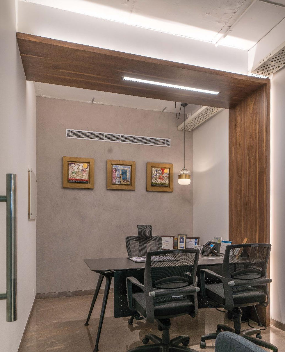 a room with two chairs and a desk with three framed pictures on the wall