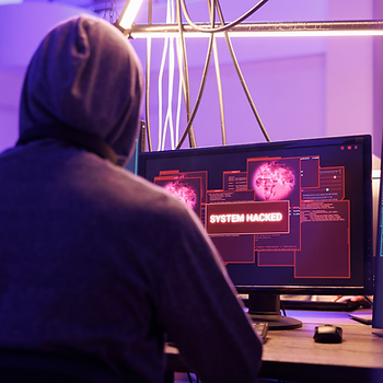 A man in a hooded sweatshirt hacks into a system.