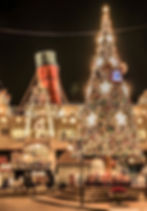 Festive Christmas tree adorned with lights and ornaments stands in front of U.S. Steamship Co. at night, creating a warm holiday ambiance.