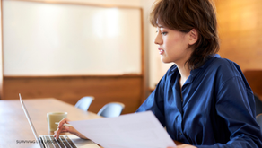 A focused professional reviews documents while working on a laptop in a modern office setting, embodying concentration and productivity.