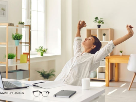 A woman sits at her desk in an office, leaning back in her chair with her arms open and eyes closed, expressing relief and empowerment as she breaks free from people-pleasing and reclaims her sense of self.