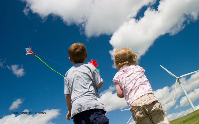 Two children fly a kite under a bright blue sky, enjoying the simple joy of childhood and freedom.