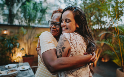 Two women share a warm embrace outdoors, expressing love, comfort, and genuine connection.