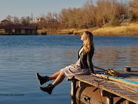 A woman sits alone on a pier, gazing at the water, reflecting a moment of self-forgiveness and acceptance for past mistakes.