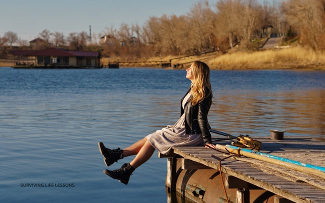A woman enjoys the sunshine while relaxing by the lake.
