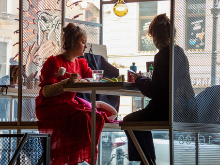 A supervisor talking with an employee at a breakroom table, both looking emotionally tired but engaged in conversation