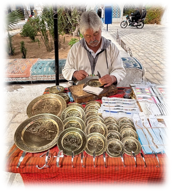 Un homme grave des motifs sur des plateaux dorés.