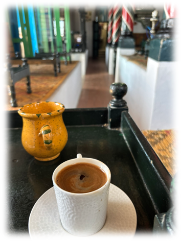 Tasse de café sur un plateau noir avec un pot jaune. Intérieur coloré d'un café, ambiance chaleureuse et détendue.