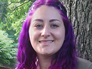 Portrait of Adrianna Powell, LSW, a therapist with long purple hair, smiling outdoors beside a tree in Champaign, IL.