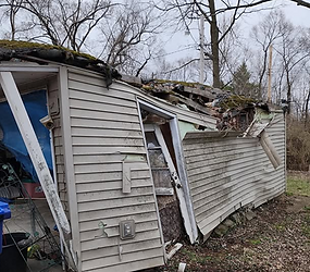 Collapsed building with damaged roof and broken siding