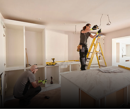Two workers remodeling a room, installing cabinets and wiring