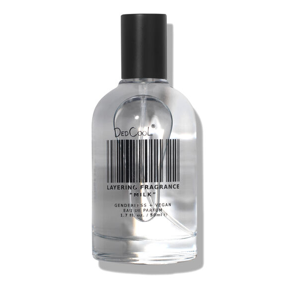 Clear glass fragrance bottle with black cap, barcode design, labeled "DedCool Layering Fragrance Milk." Text: "Genderless + Vegan."