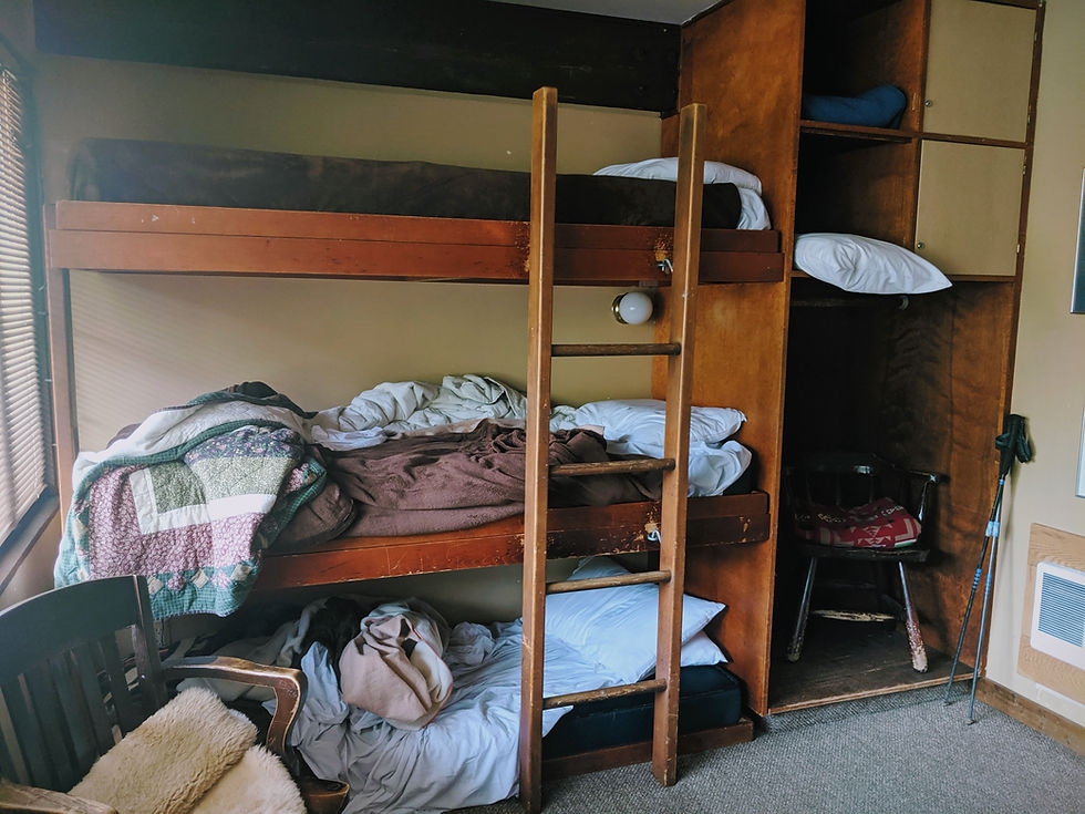 triple bunk bed with two unmade beds