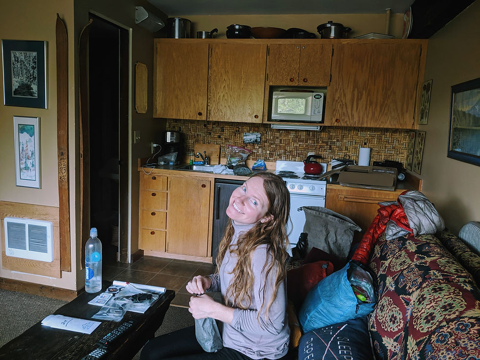Cheer sits on the couch with hiker gear splayed out next to her.