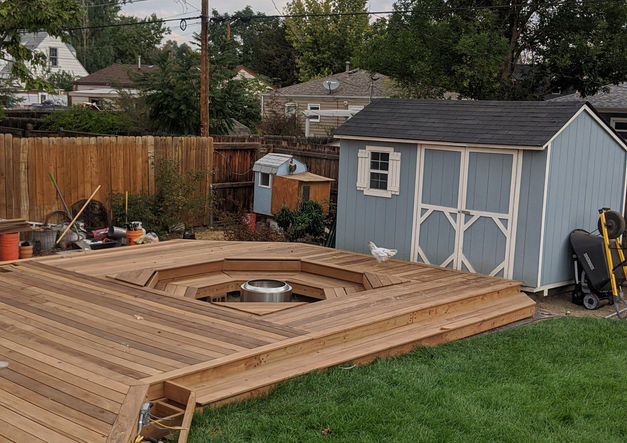 Wooden deck with built-in fire pit and shed.