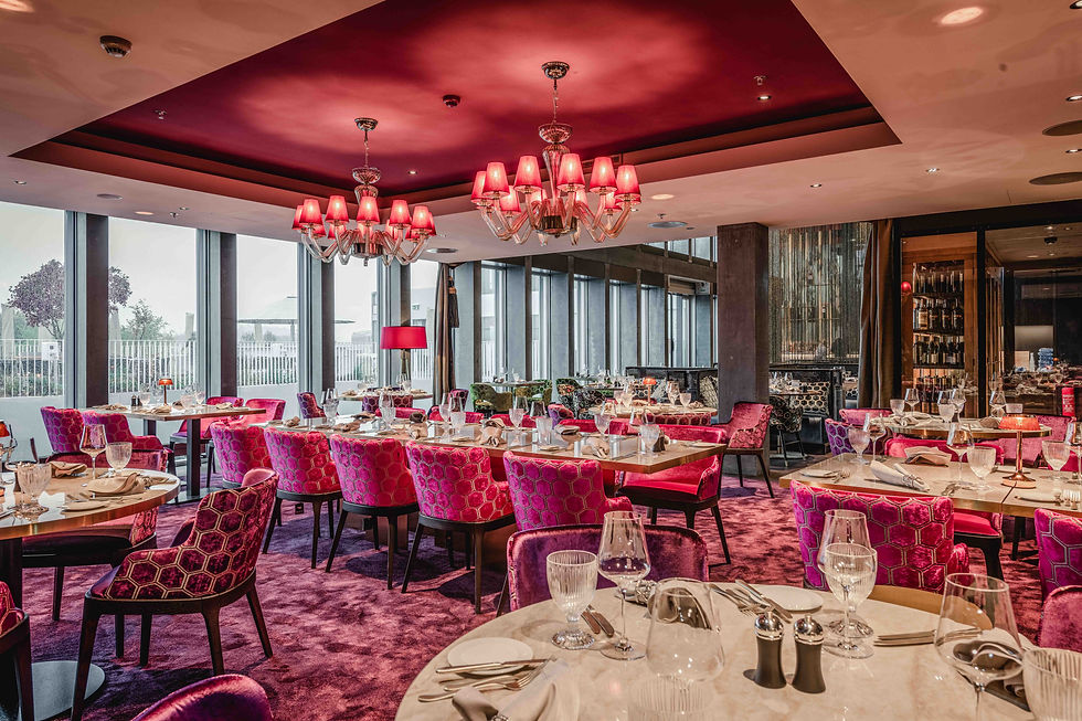 Elegantes Restaurant mit pinken Stühlen und Kronleuchtern. Gedeckte Tische, große Fenster mit Aussicht. Luxuriös und gemütlich.