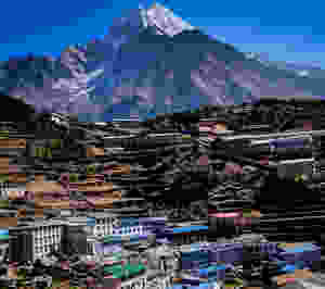 Huge snow-capped mountain and a mountain settlement in Nepal Himalayas