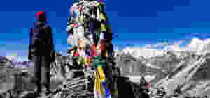 A dome of prayer flags on top of a mountain with a woman standing next to it