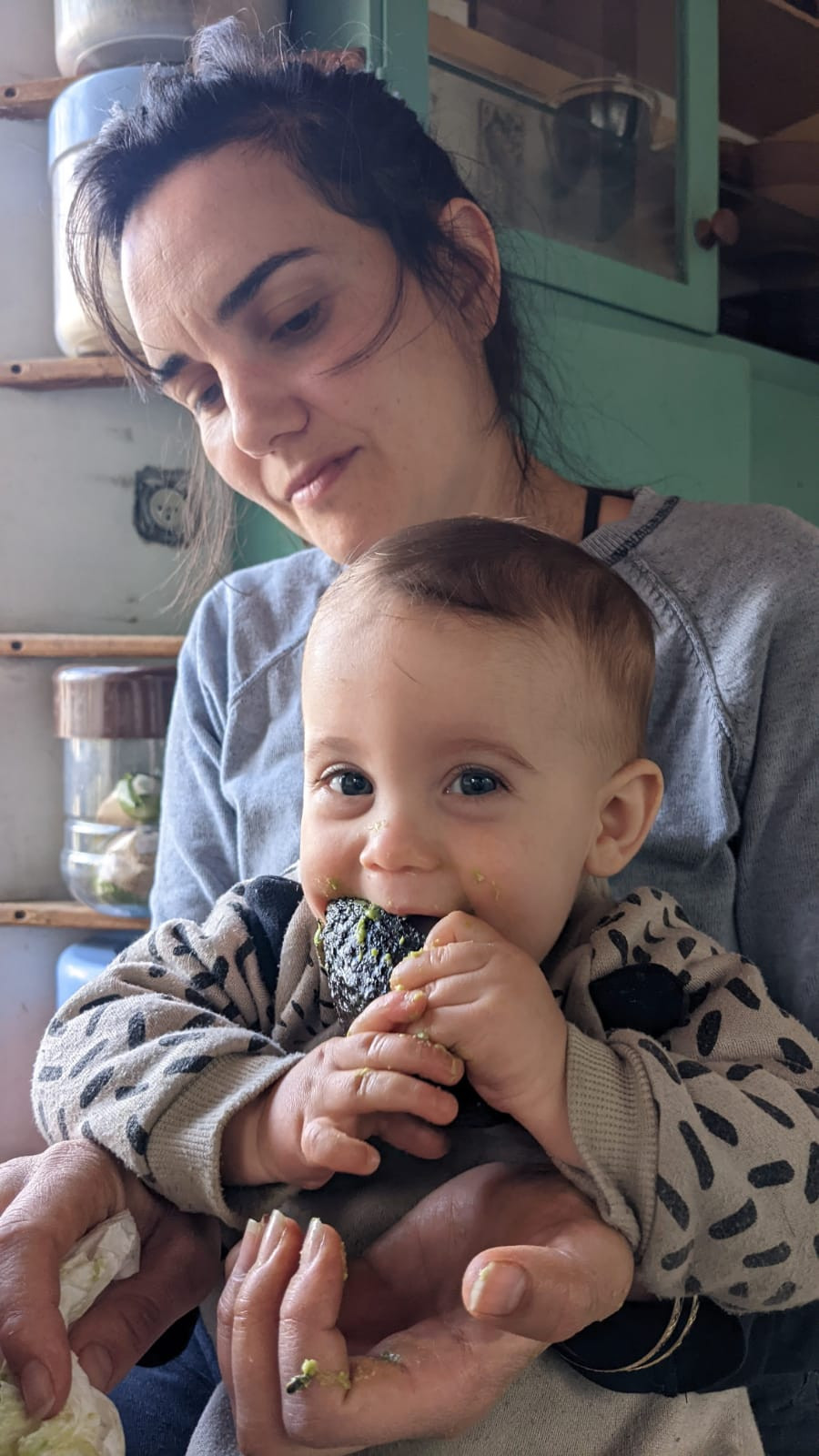 baby sits and eat on mom lap