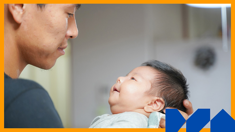 A person holds a smiling baby indoors, creating a tender scene.