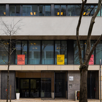 Fachada de um prédio com várias bandeiras do projeto Poesia Estendida, com versos de poesia pendurados nas janelas.
