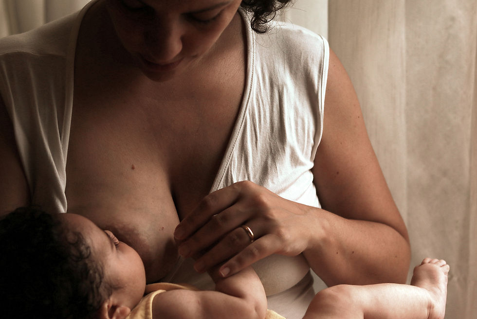 Moeder en pasgeboren baby met donkere huid en donker haar, baby drinkt aan moeders ontblote borst terwijl mama baby's handje vasthoudt