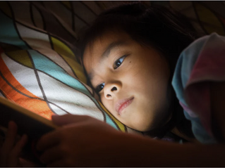 Une petite fille dans son lit sur un téléphone