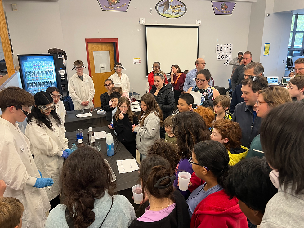 Students gathering around a table to watch a chemistry experiment