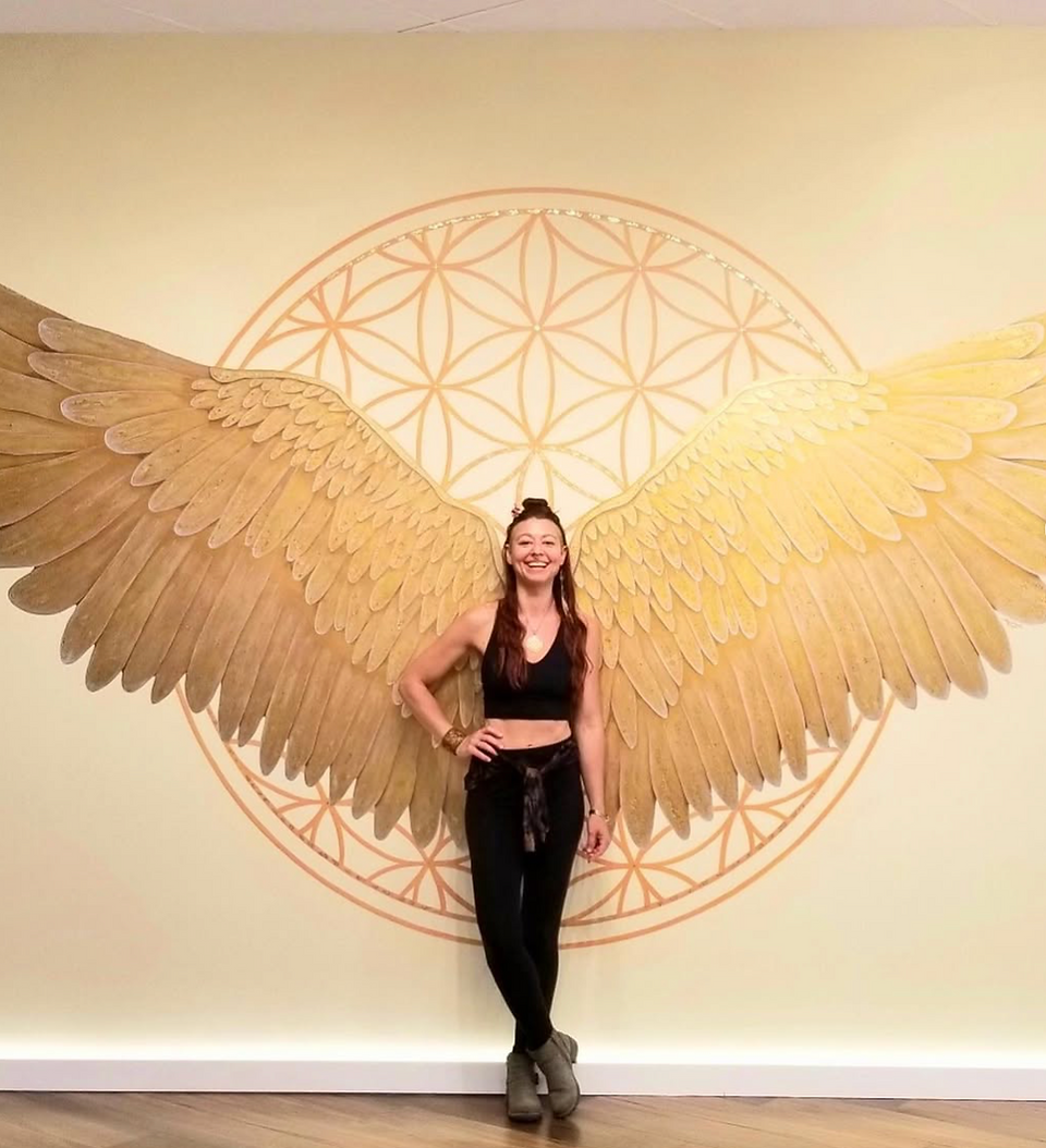 large mural of wings with a woman standing in front of it