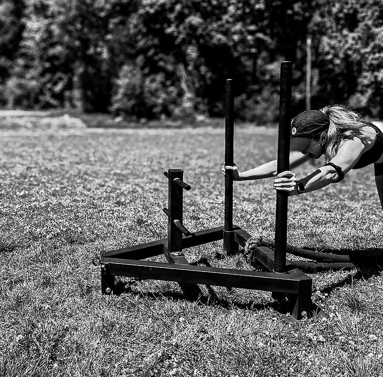 Black and white photo of outdoor functional training with sled equipment
