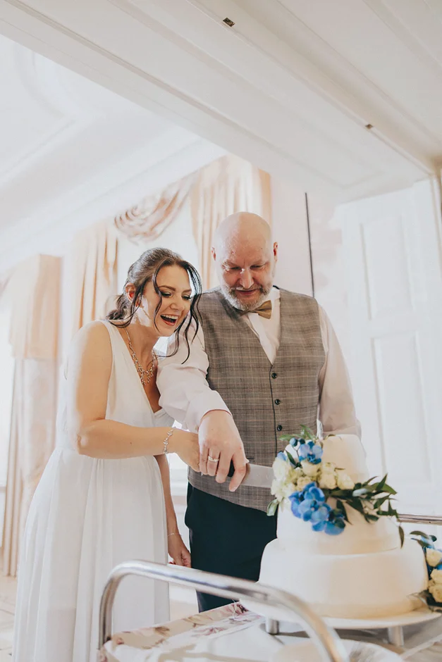 lenerowa ceremonia pod błękitnym niebem, wejście Pary Młodej wśród kwiatów, ikoniczny Cadillac Sedan DeVille przed pałacem, pałacowe wnętrza pełne blasku.