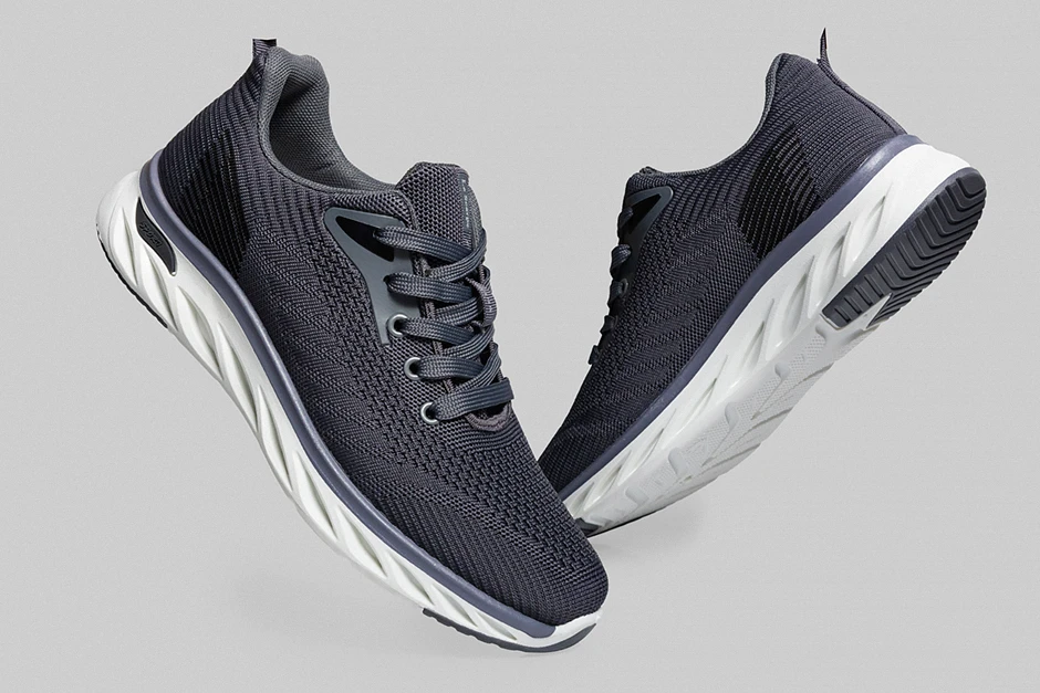 Para nowoczesnych sneakersów ustawiona centralnie na intensywnie niebieskim tle, miękkie światło podkreśla fakturę skóry i detale podeszwy.