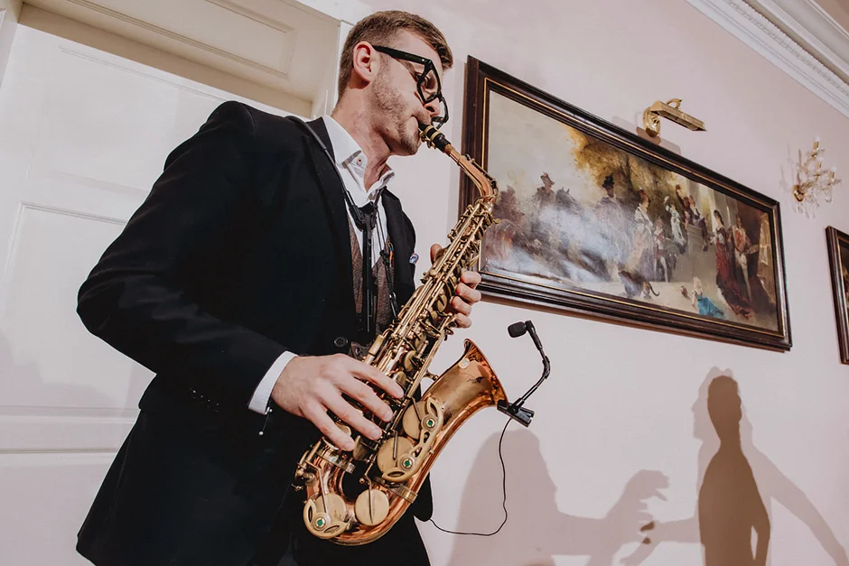 lenerowa ceremonia pod błękitnym niebem, wejście Pary Młodej wśród kwiatów, ikoniczny Cadillac Sedan DeVille przed pałacem, pałacowe wnętrza pełne blasku.