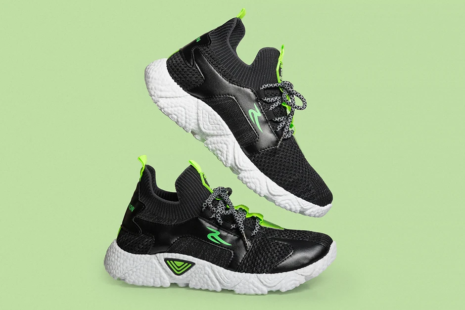 Para nowoczesnych sneakersów ustawiona centralnie na intensywnie niebieskim tle, miękkie światło podkreśla fakturę skóry i detale podeszwy.