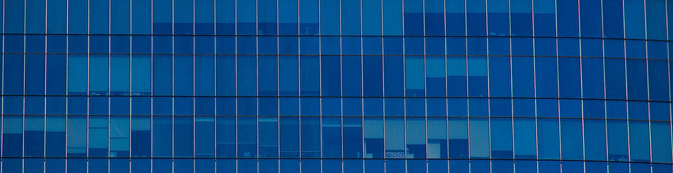 Modern glass office building with repeating blue-tinted window panels, symbolizing clarity, structure, and corporate focus—al