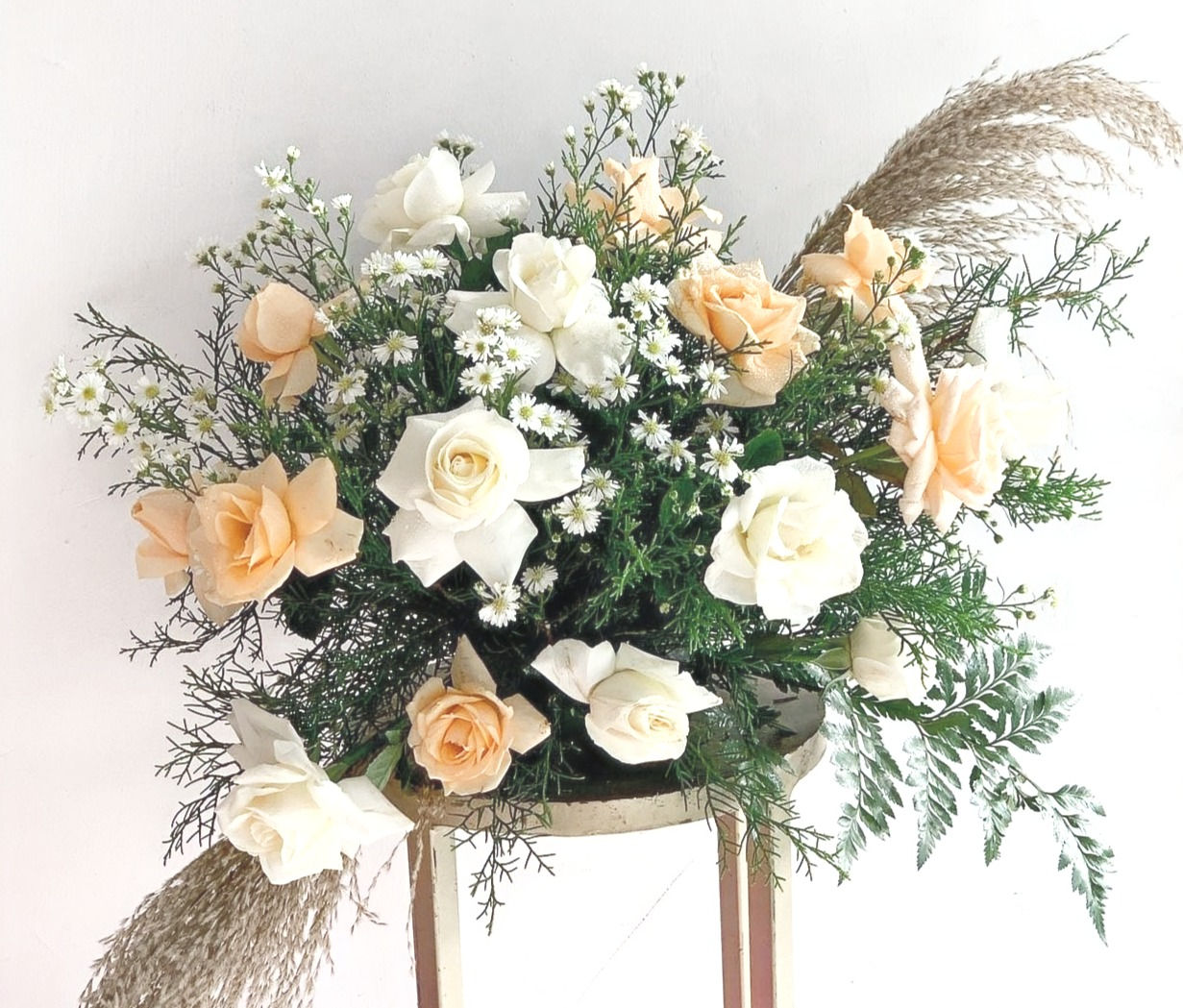 זר-פרחים-מעוצב-בגווני-לבן-ובז-כולל-ורדים-בצבע-בז-ולבן-עם-ענפי-אורן-וגיפסופילה,-בסלסלה