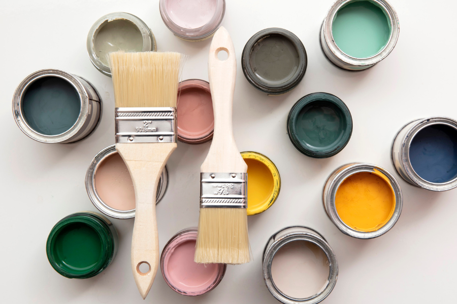 Open paint cans with pain and paint brushes laying on top