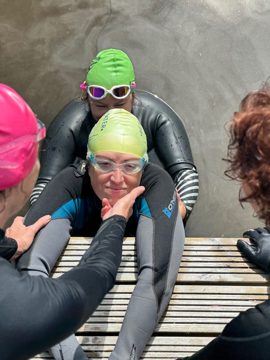 Swimmers and tutor practising an assisted rescue at the edge of a pontoon.