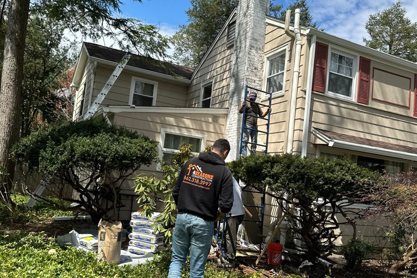 Masonry contractor repointing chimney mortar joints on a Wayne NJ home